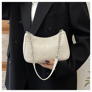 Detail of cream crossbody bag with silver chain and textured finish on black blazer
