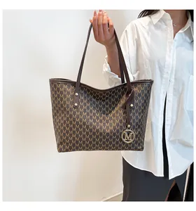 Detail einer braunen Shopper-Tasche mit M-Print und goldenem Logo-Anhänger