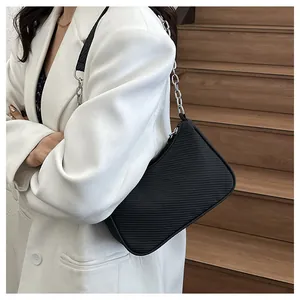 Chic black woven underarm bag with silver chain strap worn with a white blazer