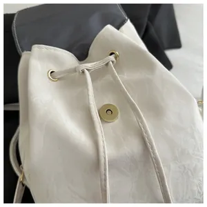 Dettaglio dello zaino bianco a coulisse con trama vintage e fibbia magnetica dorata
