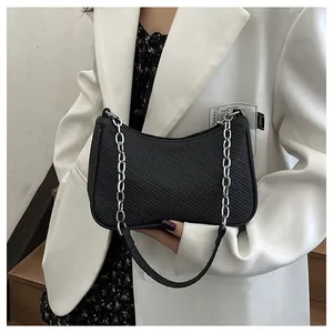 Detail of black textured hobo bag with silver chain strap worn with a white blazer