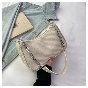 Top view of beige textured hobo bag with silver chain strap on denim fabric