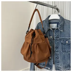 Bruine nylon emmertas met trekkoord, gepresenteerd op een rek met een denim jack