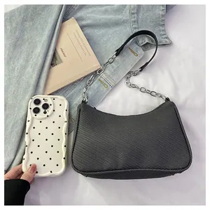 Detail of black woven shoulder bag size comparison with a phone and silver chain