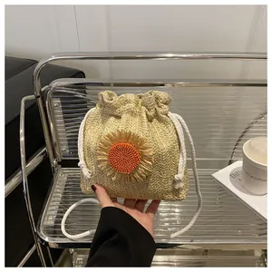 Dettaglio borsa a secchiello in paglia con girasole e coulisse in cotone bianco