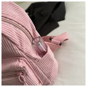 Detailansicht des rosa Cord-Rucksacks mit Seitentasche und weicher gestreifter Stoffstruktur