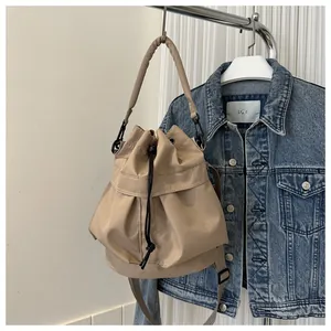 Detail van beige nylon emmertas met gewatteerd handvat en verstelbare schouderriem