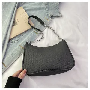 Detail of black crescent shoulder bag with silver chain strap on denim jacket and white fabric