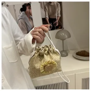 Dettaglio di un secchiello in paglia con un grande girasole e manico a coulisse bianco