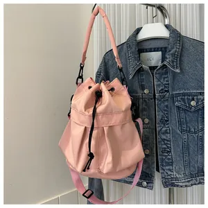 Detailopname van roze nylon emmertas met verstelbare riemen en zwarte trekkoordsluiting