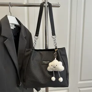 Minimalist black tote bag with silver chain strap and white plush cloud charm on a stand