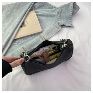 Detail view of black textured mini bag interior showing capacity for makeup and phone
