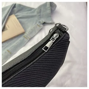 Detail of silver metal zipper and textured fabric with leather trim on a black handbag