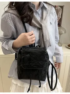 Mini zaino nero chic con trama increspata e coulisse indossato da una modella