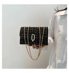 Détail d'un sac bandoulière en tweed noir et doré avec une élégante chaîne en métal
