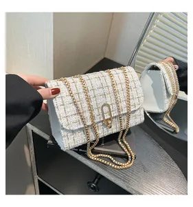 Détail du sac bandoulière en tweed blanc avec chaîne dorée et fermoir rotatif en métal