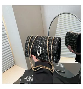 Détail de la texture en tweed noir et doré avec fermoir argenté sur un sac à bandoulière