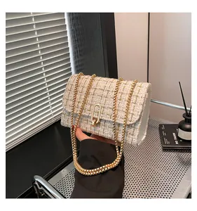 Gros plan sur le sac bandoulière en tweed blanc cassé avec chaîne et boucle dorées
