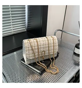 Gros plan d'un sac en tweed crème avec chaîne dorée et fermoir rotatif élégant en métal