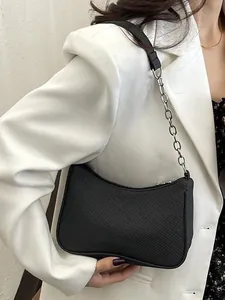 Minimalist black canvas underarm bag with silver chain strap worn by a model