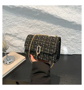 Détail du sac bandoulière en tweed avec garnitures dorées et bandoulière chaîne à la main