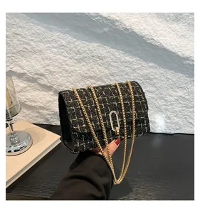 Détail de la texture en tweed noir et doré avec chaîne élégante et boucle ovale dorée