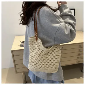Detail of hand-woven crochet tote bag with brown leather straps shown on shoulder