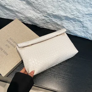 White crocodile-embossed crossbody pillow bag with gold rings and folding design