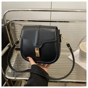 Detail of a minimalist black saddle bag with a golden buckle on a stylish background