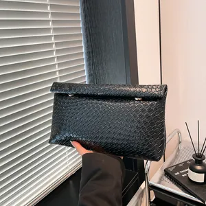 Women's black woven crossbody bag with metallic studs and elegant flap closure