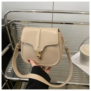 Detailed view of beige saddle bag with smooth leather texture and golden metal lock buckle