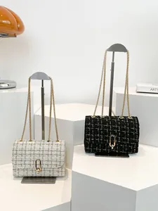 Sac à bandoulière chic en tweed avec boucle en U dorée sur un présentoir