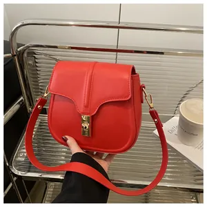 Detail of red leather saddle bag featuring a gold metal buckle and smooth texture