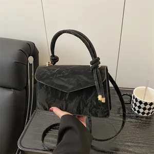 Schwarze Umhängetasche aus gerafftem Leder mit Knotengriff und goldenen Metalldetails