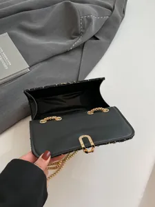 Sac bandoulière en tweed noir avec chaîne dorée et fermoir métallique en vue ouverte