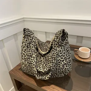 Leopard print canvas tote bag with half-moon shape on wooden table for casual daily use