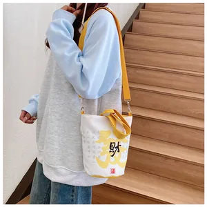 Details zur Canvas-Beuteltasche mit gelbem Gurt und Kalligrafie-Druckdesign