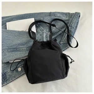 Detailansicht der schwarzen Nylon-Beuteltasche mit Netztasche auf einer Denim-Jacke