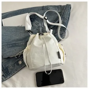 Detailansicht der weißen Nylon-Beuteltasche mit Fashion-Label und seitlicher Netztasche
