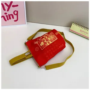 Detailansicht der roten Canvas-Beuteltasche mit goldenen Schriftzeichen und gelbem Gurt