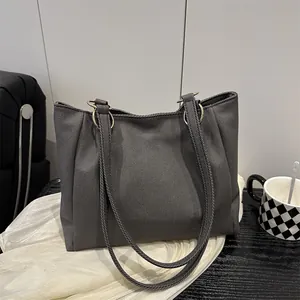 Sac cabas en toile gris foncé avec texture rayée et anneaux métalliques sur bureau minimaliste