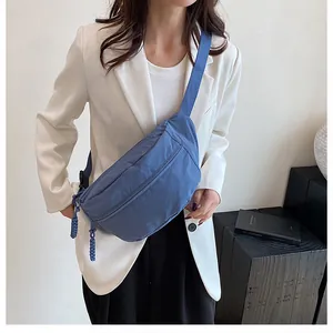 Detail of blue nylon crossbody bag featuring braided zipper pulls and wide strap