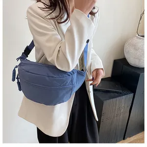 Detail showing blue nylon crescent bag with adjustable strap and braided zipper pull