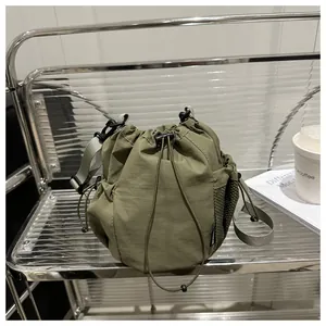 Olivgrüne Nylon-Beuteltasche mit Kordelzug und Netztasche im minimalistischen Regal