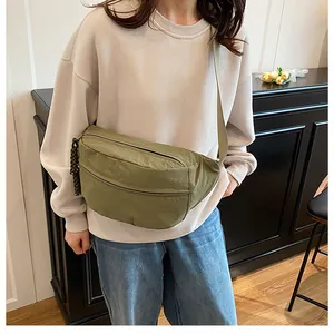 Close-up of olive green nylon crossbody bag showing crescent shape and woven zipper detail