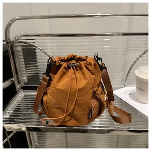 Detailansicht der Nylon-Beuteltasche in Karamell mit Netztasche auf einem minimalistischen Regal
