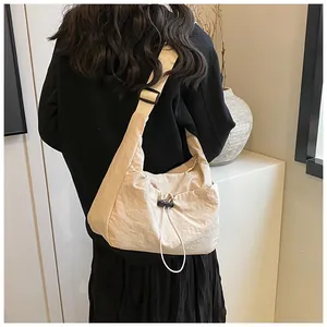 Dettaglio della borsa in nylon plissettato beige con coulisse decorative e ampia tracolla nera