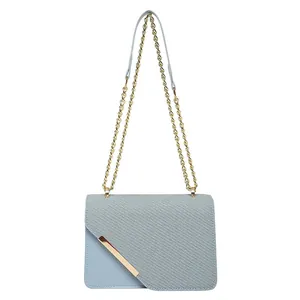 Light blue crossbody bag with gold chain strap and asymmetrical flap on white background