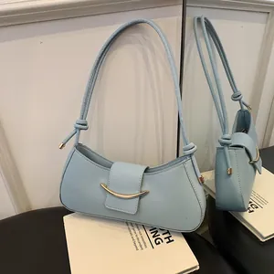 Light blue shoulder bag with golden crescent buckle and knotted straps in mirror view