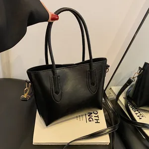 Grand sac cabas noir en similicuir avec détails dorés sur un socle de livres